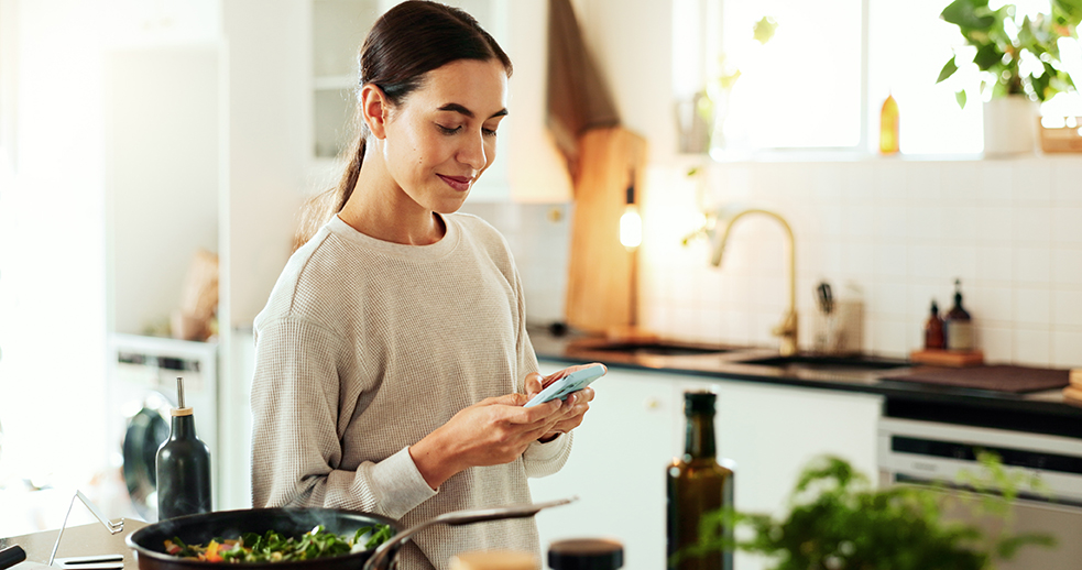Woman, cooking and online with phone in kitchen for healthy salad recipe, meal prep or ingredients search